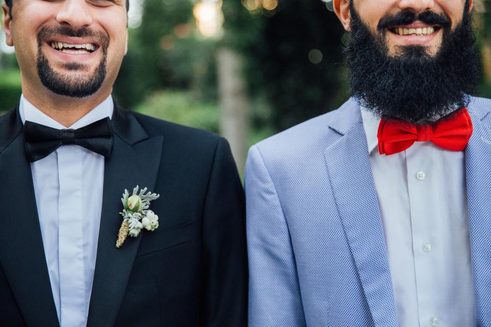 Two smiling men in a dinner suit and a blue suit with bow ties